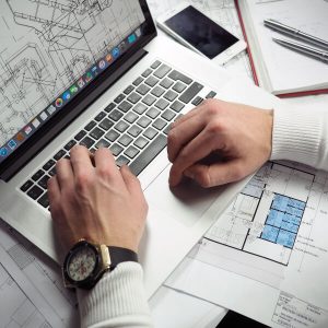 Person working on blueprints on a laptop