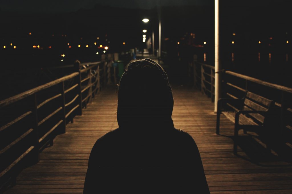 Person walking alone down dark dock